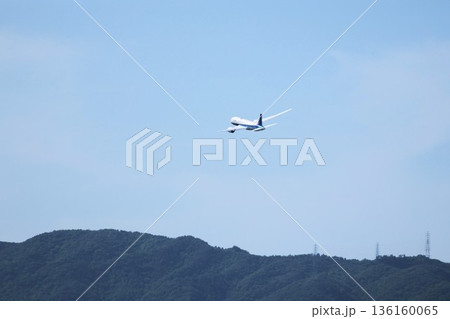 大阪・伊丹空港の滑走路から離陸して旋回していく飛行機 136160065