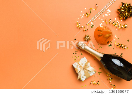 Flat lay composition of Champagne bottle gift box ribbons and confetti on colored background. Flat lay, top view holiday concept Flat lay composition of Champagne bottle gift box ribbons and confetti on colored background. Flat lay, top view holiday concept 136160077