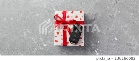 Valentine or other holiday handmade present in paper with red hearts, car keys and gifts box in holiday wrapper. box gift on gray cement table top view with copy space, empty space for design Valentine or other holiday handmade present in paper with red hearts, car keys and gifts box in holiday wrapper. box gift on gray cement table top view with copy space, empty space for design 136160082