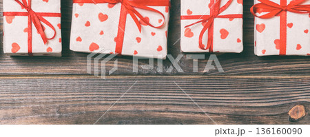 valentine or other holidays concept. Lots of Gift boxes on wood background top view. Presents in craft paper decorated with red ribbon bows and heart. Top view frame with copy space valentine or other holidays concept. Lots of Gift boxes on wood background top view. Presents in craft paper decorated with red ribbon bows and heart. Top view frame with copy space 136160090