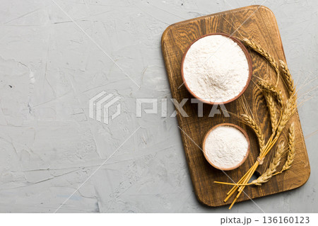 Flat lay of Wheat flour in wooden bowl with wheat spikelets on colored background. world wheat crisis Flat lay of Wheat flour in wooden bowl with wheat spikelets on colored background. world wheat crisis 136160123