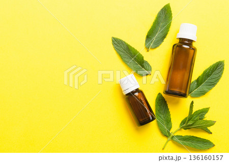 Natural Mint Essential Oil in a Glass Bottle. organic cosmetics with herbal extracts of mint on colored background 136160157
