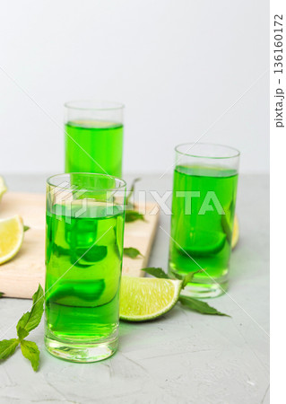 Sweet refreshing mint liqueur, with ice and mint leaves on table background, Shots with lime slice and mint flat lay Sweet refreshing mint liqueur, with ice and mint leaves on table background, Shots with lime slice and mint flat lay 136160172