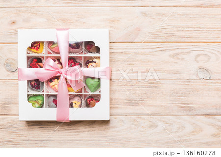 Box with sweet chocolate candies on color background, Various candy sweets. Valentines day gift box. Top view flat lay with copy space Box with sweet chocolate candies on color background, Various candy sweets. Valentines day gift box. Top view flat lay with copy space 136160278