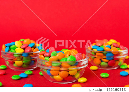 Multicolored candies in a bowl on a colored background. birthday and holiday concept. Top view with copy space 136160518