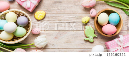 Easter frame with eggs, gift box and tulip on a colored background. The minimal concept. Top view Happy Easter composition. Card with a copy space of the place for the text 136160521