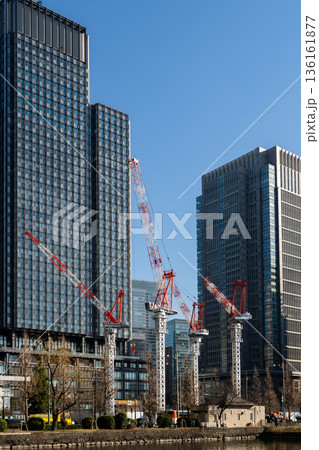 水辺に並ぶ建設クレーンと近代的な高層ビル群の風景 水辺に並ぶ建設クレーンと近代的な高層ビル群の風景 136161877