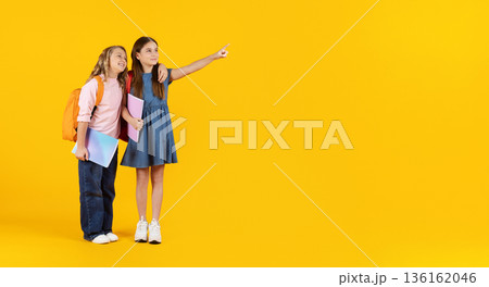 Two preteen students with backpacks pointing aside at copy space 136162046