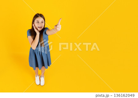 Surprised preteen girl points forward with excitement, expressing discovery and curiosity Surprised preteen girl points forward with excitement, expressing discovery and curiosity 136162049