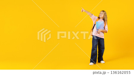 Preteen student girl pointing aside at copy space confidently while holding notebook Preteen student girl pointing aside at copy space confidently while holding notebook 136162055