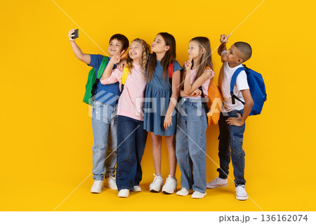 Preteen children taking selfie together on yellow studio background Preteen children taking selfie together on yellow studio background 136162074