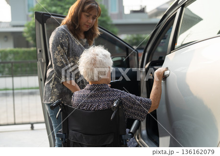 Caregiver help Asian elderly woman disability patient get in her car. 136162079