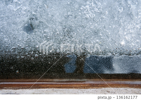 Frozen window with ice and air bubbles close up for winter background and cold weather concept with icy texture detail 136162177