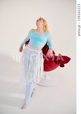 aspirational portrait white woman looking upward by red chair 136162223