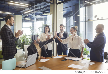 Smiling colleagues give high five and applause after successful office presentation Smiling colleagues give high five and applause after successful office presentation 136162229