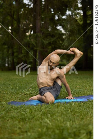 Male engaging in strength and flexibility exercise in park environment 136162245