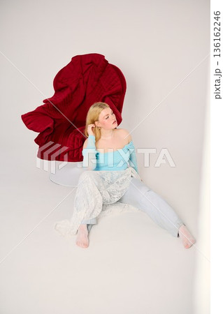 Influencer in trendy outfit sits on striking red sculpture chair 136162246