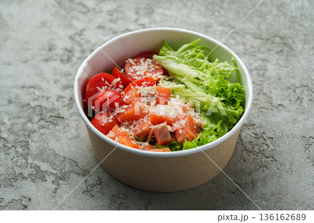 Salad made with fresh tomatoes and lettuce served in a bowl on a gray surface Salad made with fresh tomatoes and lettuce served in a bowl on a gray surface 136162689