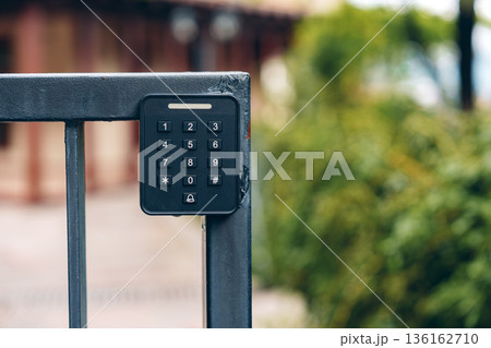 Keypad access control on a metal gate outside a building in a residential area 136162710