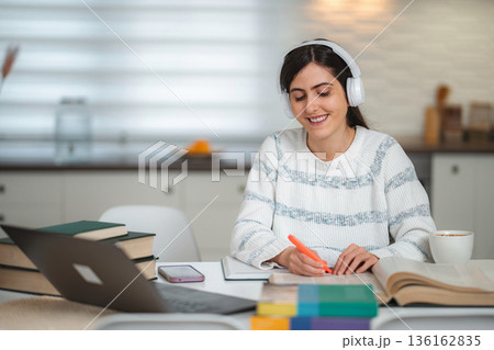 Smiling woman studying at home focused on online education Smiling woman studying at home focused on online education 136162835