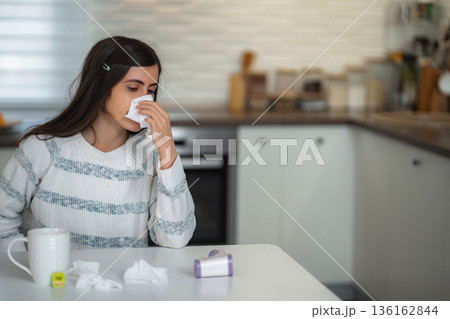 Young woman blowing nose with tissue feeling sick Young woman blowing nose with tissue feeling sick 136162844