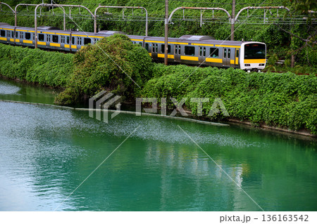 エメラルドグリーンの外濠沿いを走る中央緩行線の電車 136163542