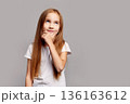 Beautiful thoughtful young girl with long hair looking up, isolated on gray studio background, expressing curiosity, imagination and creative childhood thinking in beauty child portrait 136163612