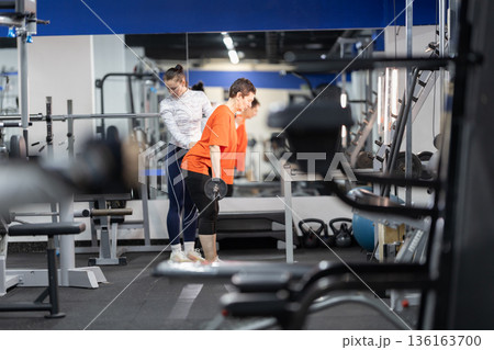 Personal trainer guiding woman during strength training workout Personal trainer guiding woman during strength training workout 136163700