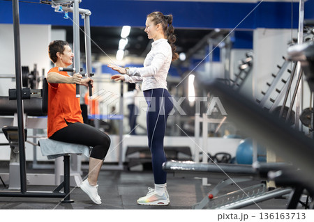 Senior woman training with personal coach in gym 136163713