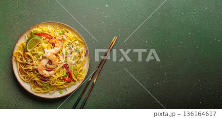 Pad thai noodles with shrimp, peanuts and lime on green background, dish of Thailand. Space for text Pad thai noodles with shrimp, peanuts and lime on green background, dish of Thailand. Space for text 136164617