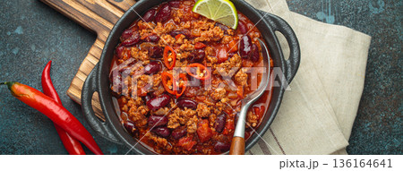 Mexican dish Chili con carne with lime, garlic and chili pepper on dark background top view 136164641