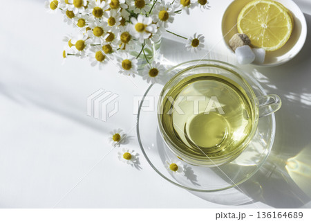 自然光と影　マトリカリアと透明なティーカップのフラットレイ 136164689