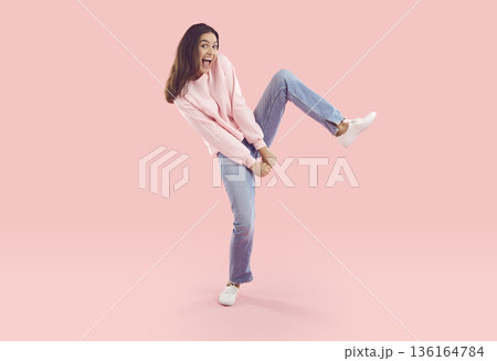 Cheerful young woman dancing standing on one leg Cheerful young woman dancing standing on one leg 136164784
