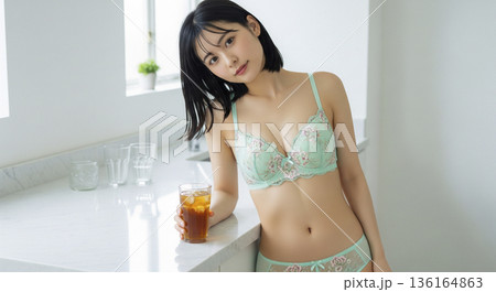 キッチンカウンターで飲み物を手に微笑むグリーンのランジェリー姿の女性 136164863