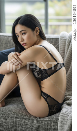 ソファの上で膝を抱えて座る黒いレース下着姿の日本人女性 136164895