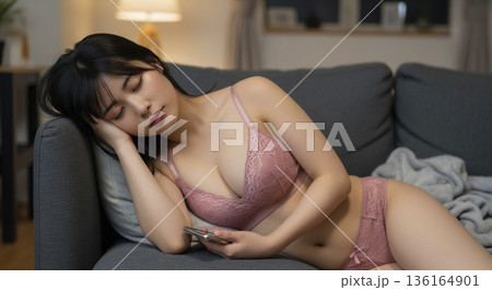 ソファでスマホを持ったまま眠るピンクのランジェリー姿の日本人女性 136164901