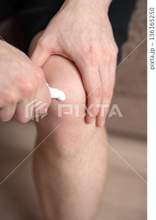 man applying ointment cream on his knee, knee pain man applying ointment cream on his knee, knee pain 136165250