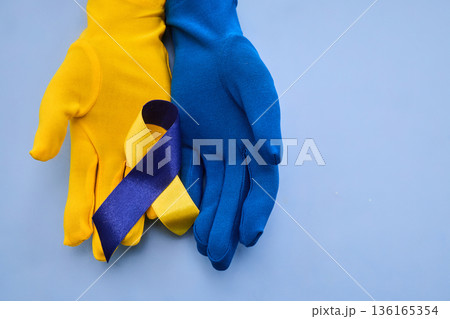 Yellow and blue gloves holding down syndrome awareness ribbon Yellow and blue gloves holding down syndrome awareness ribbon 136165354