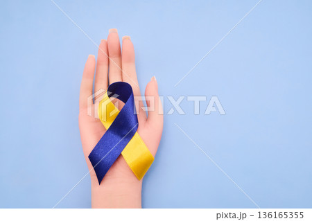 Hand holding blue yellow ribbon symbolizing ukraine solidarity 136165355