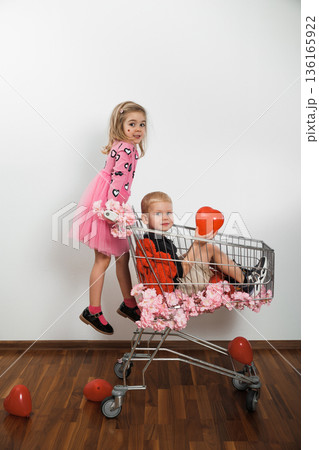 Children play with shopping cart and balloons in indoor setting during daytime Children play with shopping cart and balloons in indoor setting during daytime 136165922