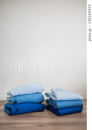 Stacked blue blankets arranged neatly on a wooden floor in a simple indoor space 136165933