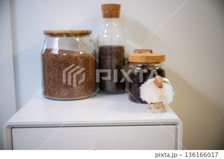 kitchen jars with grains seeds and dried berries with small sheep decor 136166017