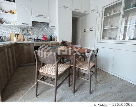 Living room design combined with kitchen, featuring white sideboard. Set of wooden furniture with beech veneer, table, and chairs. Scandinavian-style interior. Minimalism and modern renovation.  136166068