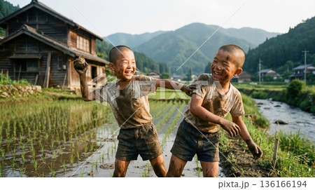 田んぼの横で泥遊びをして大はしゃぎする元気な二人の少年 136166194