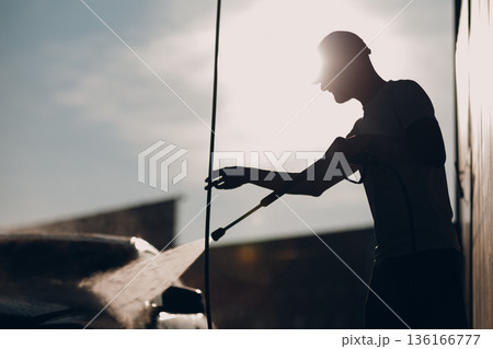 Worker man silhouette washing car at self service car wash 136166777