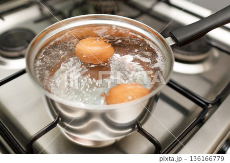 Saucepan stainless steel with boiling eggs breakfast in water on gas stove. 136166779