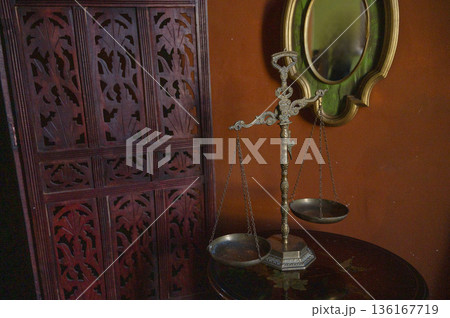 Antique bronze scales on a wooden round table. Vintage room. Antique bronze scales on a wooden round table. Vintage room. 136167719