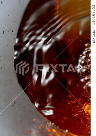 Golden drink is poured into the glass, creating beautiful waves and splashes. Golden drink is poured into the glass, creating beautiful waves and splashes. 136168352