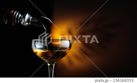 Rum being poured from a bottle into a glass. Rum being poured from a bottle into a glass. 136168353
