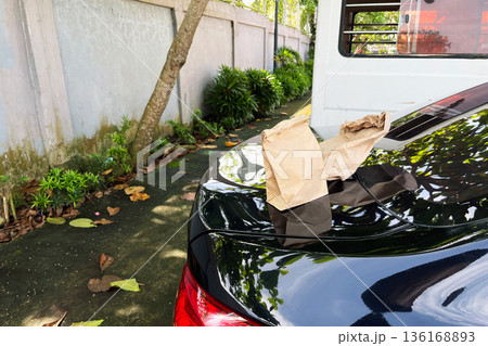 two brown paper bags sitting on the black trunk of a car in a parking lot on a sunny day, ready for delivery or takeaway two brown paper bags sitting on the black trunk of a car in a parking lot on a sunny day, ready for delivery or takeaway 136168893